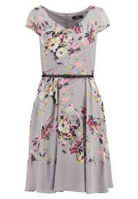 Robe florale violet clair à manches courtes, encolure en V, taille ajustée avec une fine ceinture noire, et une jupe plissée avec un ourlet uni.