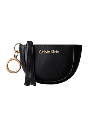 Zwarte leren polstasje in halve maanvorm met gouden Calvin Klein-logo, een gouden sleutelhanger en details van een zwarte leren band.