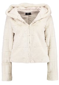 Creme, kort zip-up jakke lavet af blød, tekstureret kunstpels med en hætte. Har et quiltet mønster og lange ærmer.