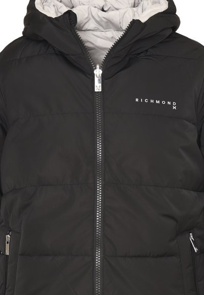 Giacca imbottita nera con interno grigio, chiusura frontale con zip e tasche laterali. Presenta un logo sul petto e un design trapuntato.