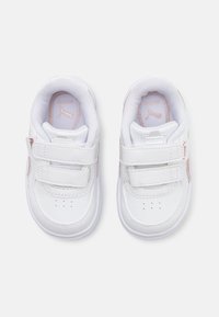 Hvite sneakers med glatt lærutside, borrelåsremmer, perforerte detaljer på tåen, og rosa aksenter på siden.