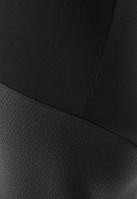 Leggings neri con una parte superiore liscia e una parte inferiore testurizzata con un motivo a diamante. Il tessuto appare elastico e aderente.