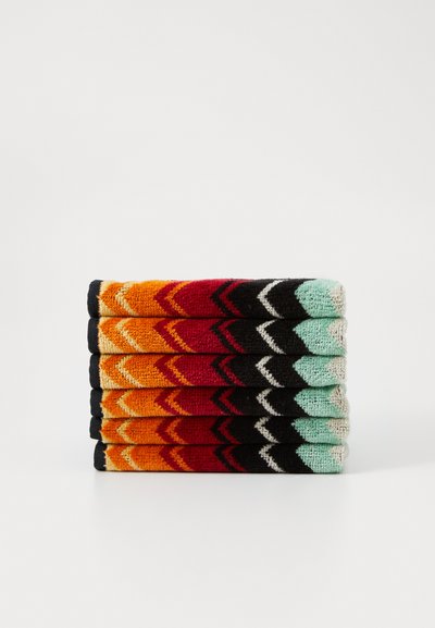 Sei paia di calzini impilati ordinatamente, con un motivo a zigzag nei colori arancione, rosso, nero e teal, dotati di risvolti neri a costine.