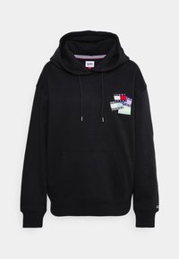 Sudadera con capucha negra hecha de algodón, que presenta un bolsillo frontal y un parche gráfico de etiquetas de colores en la zona izquierda del pecho.