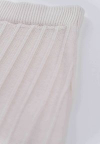 Light beige knitted fabric with vertical ribbed texture and a wide, elastic waistband. Soft, stretchy material for comfort.