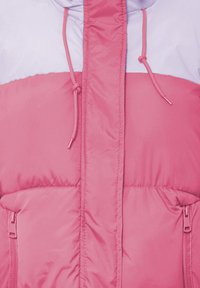 Rožinė ir levandų spalvų pūkinė striukė, su užtrauktukais kišenėse, raišteliais ant gobtuvo ir išsiuvinėtu raštu visoje striukėje.