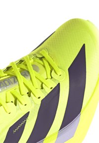 Felgeel sportieve schoen met een gestructureerd oppervlak, voorzien van grijze accenten en patroonontwerpen. Inclusief bijpassende veters en logo.