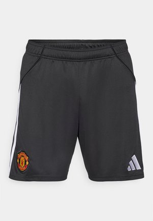 Melnas sporta bikses no gludas auduma, ar baltām sānu svītrām un sarkanu Mančestras United emblēmu apakšējā kreisajā pusē.