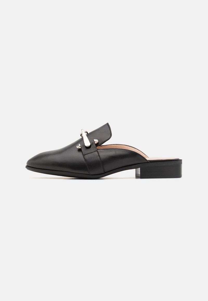 Mules en cuir noir à enfiler avec un bout pointu, un talon plat et un accent en métal argenté sur la sangle avant. Texture lisse, design minimaliste.