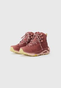 Bordeaux fotturer med en teksturert overdel, kontrasterende lysegul såle og forsterkede øyer for snøring. Vibram-logoen er synlig.
