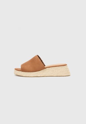 Brun ruskind åben tå slip-på sandal med en vævet jute platform kilehæl på en neutral baggrund.