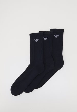 Marineblaue gerippte Socken, Baumwollmischung, mit einem kleinen weißen Logo am Bund. Set aus drei Paaren. Glattes Material und standardmäßige Form.