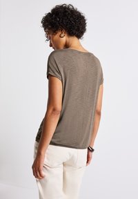 Olive green short-sleeve top with a relaxed fit and slightly textured fabric, featuring a back seam detail and round neckline.