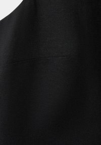 Tissu noir texturé avec une couture horizontale visible traversant le milieu du matériau.