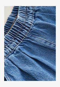 Tejido de mezclilla con cintura elástica fruncida, color azul, que muestra detalles de textura y costura. Apto para uso casual.