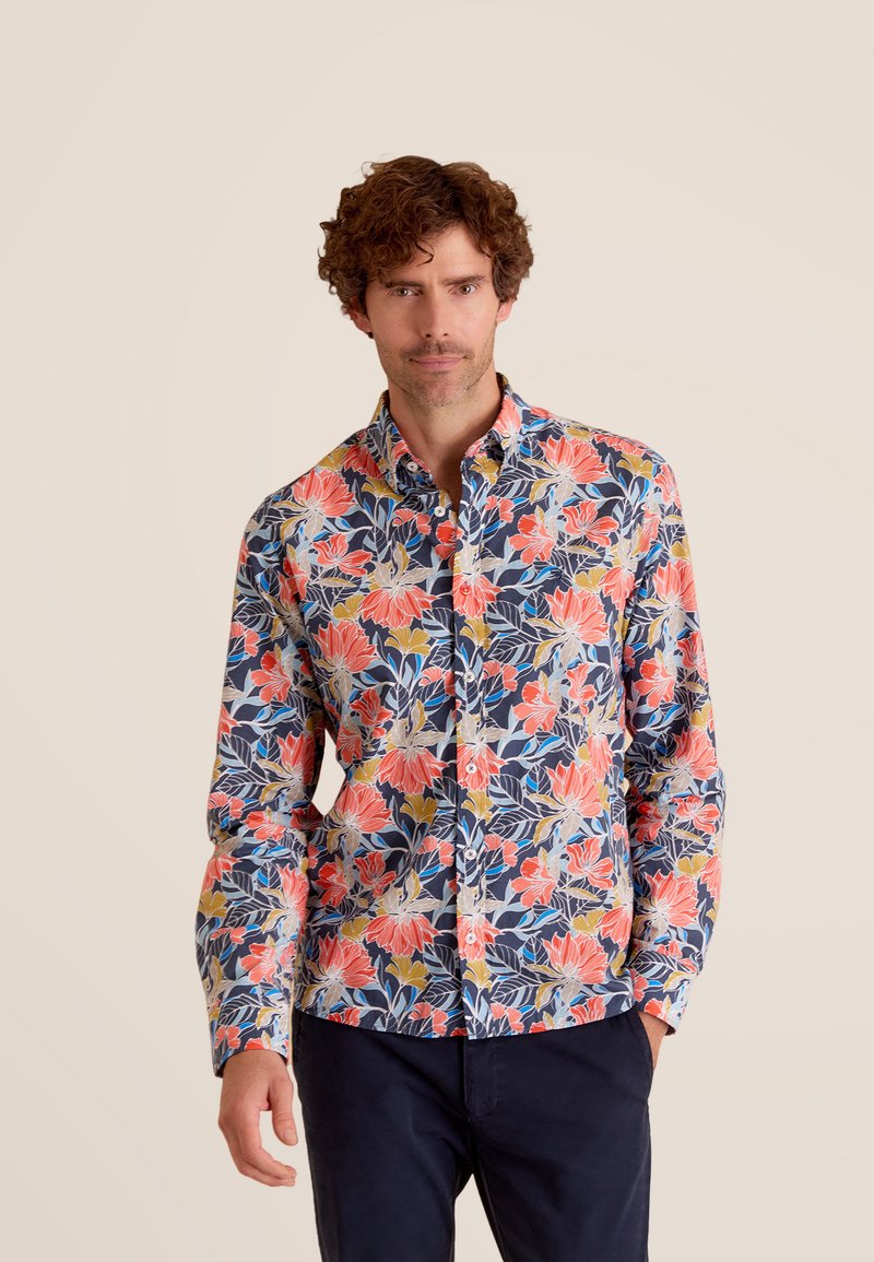 Navy bloemetjesoverhemd met grote rode en gele bloemen en groene bladeren, gemaakt van lichte stof met een zachte textuur.