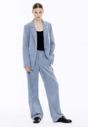 Light blue corduroy blazer and matching wide-leg trousers, featuring a smooth texture and single-button closure, paired with a black top.