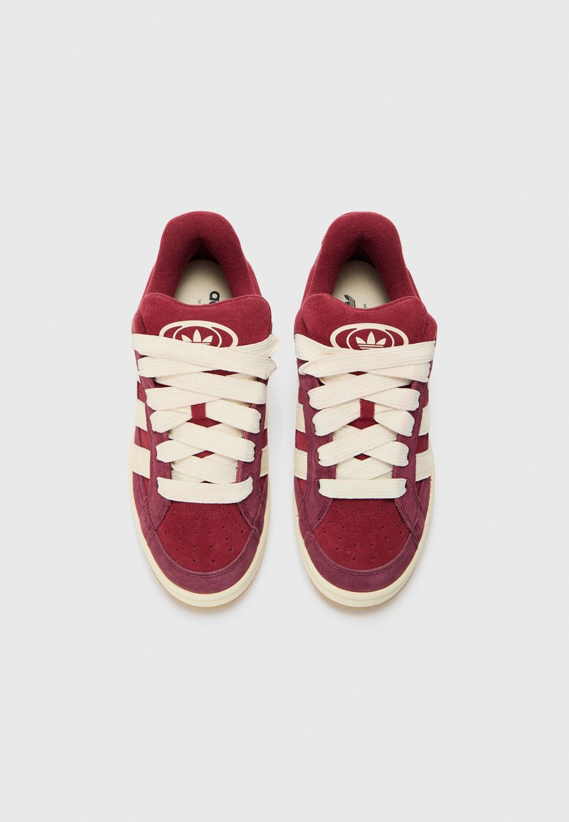 Baskets en suede bordeaux avec des lacets crème et trois bandes sur les côtés. Présente une zone de orteils perforée et un logo sur la languette.
