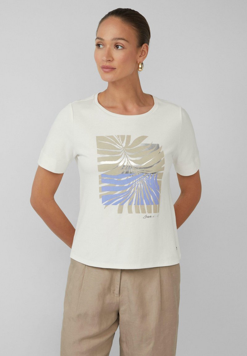 T-shirt en coton blanc à manches courtes, avec un imprimé abstrait de feuilles dorées et bleues sur le devant, col rond et coupe décontractée.