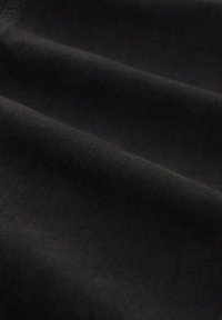 Tessuto di cotone nero con una consistenza morbida, che presenta pieghe sottili e una finitura liscia, adatto per varie applicazioni di abbigliamento.