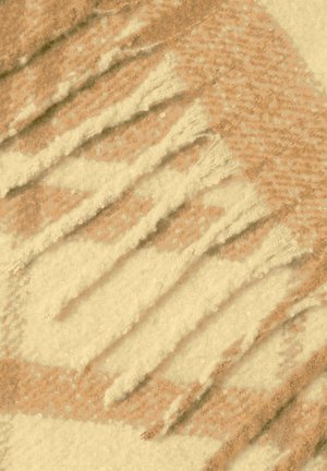 Tissu à motifs beige clair et tan avec des détails en franges, présentant une texture douce et un design géométrique angulaire.