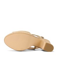 Sandale à talon compensé beige vue de la semelle, avec une plateforme texturée et un talon bloc, avec bride à la cheville et boucle.