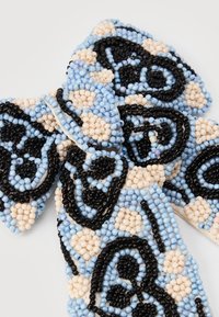 Beaded accessory z okrasnim cvetnim vzorcem. Barve vključujejo črno, svetlo modro in smetanasto. Material je sestavljen iz majhnih, gladkih kroglic.