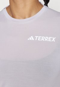 T-shirt Terrex lilás claro com gola redonda e um logótipo branco no lado esquerdo do peito, feito de um tecido suave e respirável.