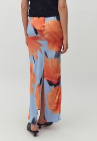 Floral maxirok in lichtblauw met grote oranje bloemen, voorzien van een zijschede en gemaakt van soepele, lichte stof. Zwarte blokhak schoenen.