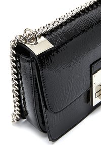 Bolso de mano de charol negro con un diseño estructurado, que cuenta con una correa de cadena plateada y acentos metálicos rectangulares en el frente.