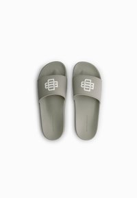Slide sandals in light green with a matte finish. Features a wide strap with a white logo and a textured footbed for grip.