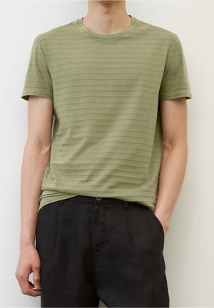 Olivek zielony pasiasty t-shirt z miękkiej tkaniny z krótkimi rękawami i okrągłym dekoltem, zestawiony z ciemnymi spodniami. Delikatna tekstura na całej powierzchni.