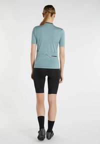 Maillot de cyclisme bleu clair à manches courtes avec un col noir, associé à un short noir rembourré avec des accents texturés et des détails réfléchissants.