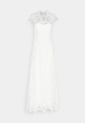Vestido branco de renda com um decote alto e mangas curtas; apresenta padrões florais e uma silhueta fluida, terminando numa barra em ondulação.