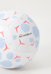 Hvid fodbold med blå og røde hexagonale mønstre, der har en tekstureret overflade og "Nike Academy" branding i sort.