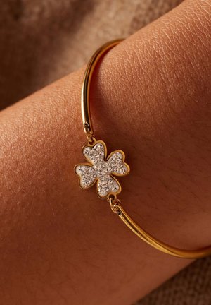 Gouden armband met een vierbladige klaverthema, versierd met sprankelende rhinestones en bevestigd met twee kleine lussen.