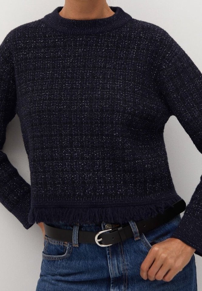 Pull court bleu marine en maille texturée, doté d'un col côtelé et d'un ourlet à franges. Porté avec un jean taille haute et une ceinture noire.