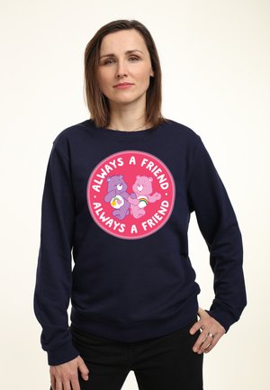 Marine sweatshirt med et cirkulært grafik, der viser to tegneserie-bjørne, som holder hjerter og regnbuer. Teksten lyder "Altid en ven." Blødt materiale.