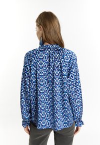 Blusa a maniche lunghe con un design a motivo blu e bianco, con polsini arricciati e una vestibilità ampia, realizzata in tessuto leggero.
