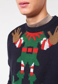 Pull en maille bleu marine avec un motif festif d'elfe vert, des accents rouges, des rayures blanches et un détail de ceinture noire.