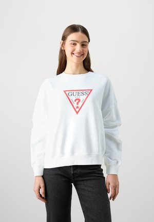 Sweatshirt blanc avec un logo triangulaire rouge et noir "GUESS" sur le devant, doté de manches longues et de bords côtelés aux poignets et à l'ourlet.