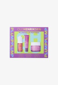 Hautpflege-Set mit drei Produkten: einer Glasflasche, einer Cremetube und einem Glas, alle in verschiedenen Rosatönen, präsentiert auf einer farbenfrohen Box.
