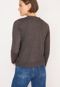 Maglione a maglia marrone con colletto tondo, polsini e orlo a costine, abbinato a jeans in denim blu con un classico design a cinque tasche.