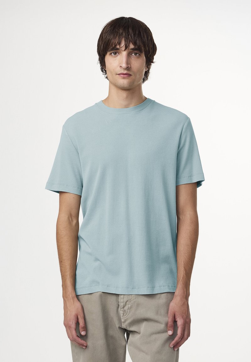 Ljusblå, kortärmad t-shirt med textilstruktur, rundad halsringning och avslappnad passform, tillsammans med beige byxor.