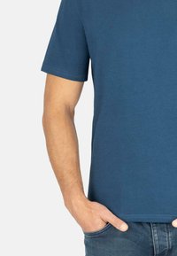 Dunkelblaues Baumwoll-T-Shirt mit kurzen Ärmeln, Rundhalsausschnitt und lockerem Schnitt. Mit sichtbaren Nähten und in Kombination mit Jeans getragen.