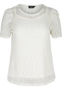 Top in pizzo bianco con maniche corte, caratterizzato da pattern intricati, scollatura arrotondata e una texture leggermente trasparente. Etichetta del marchio visibile.