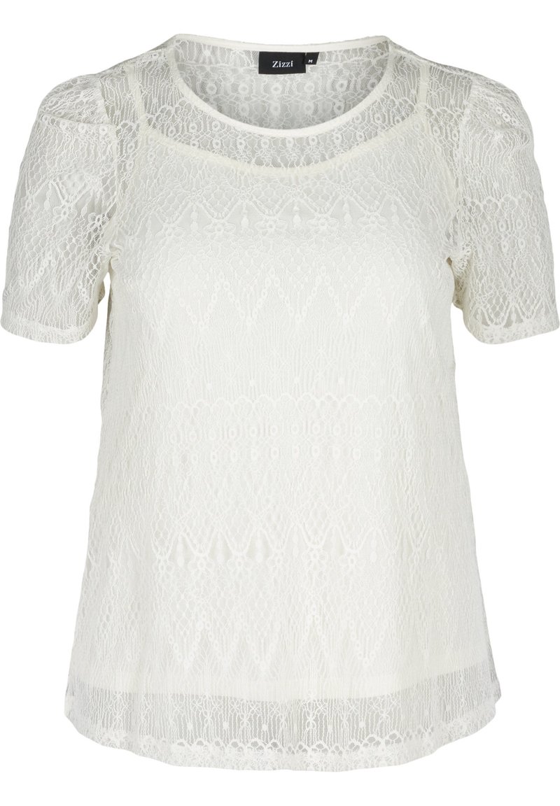 Top in pizzo bianco con maniche corte, caratterizzato da pattern intricati, scollatura arrotondata e una texture leggermente trasparente. Etichetta del marchio visibile.