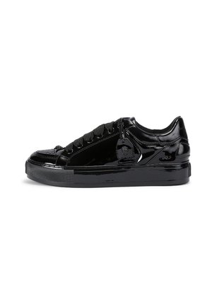 Glossy black low-top sneaker with thick sole, black laces, textured toe cap, and attached black tag detailing on the side.