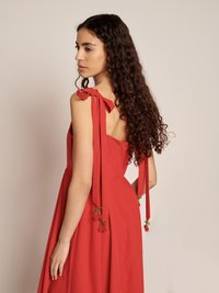 Vestido vermelho com laços nos ombros, apresentando detalhes de cerejas em pérolas. Tecido suave com um design fluido e cintura ajustada.