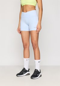 Σορτσάκια Nike σε ανοιχτό μπλε χρώμα με ψηλή μέση, συνδυασμένα με μαύρα αθλητικά παπούτσια και λευκές κάλτσες με μαύρο λογότυπο.